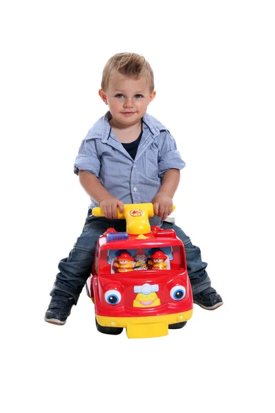 Little boy playing on a toy fire engine — Stock Photo, Image