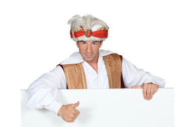 Man in a fancy dress turban giving the thumbs up to a board left blank for your image clipart