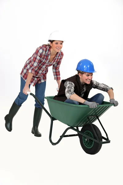 Duas mulheres trabalhadoras de construção correndo em um carrinho de mão . — Fotografia de Stock