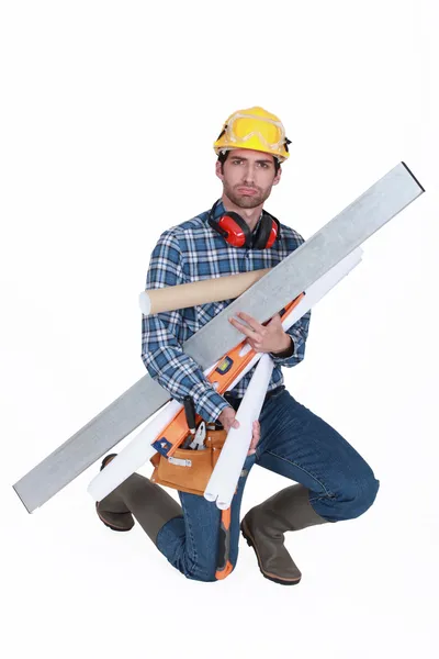 A glowering tradesman carrying building supplies — Stock Photo, Image