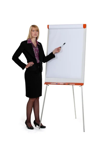 Businesswoman pointing at paperboard with marker — Stock Photo, Image