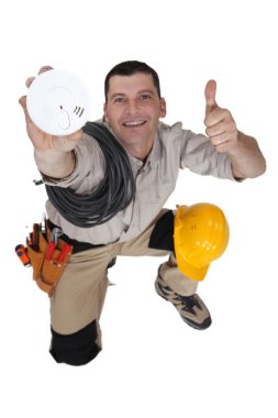 Tradesman holding up a smoke detector clipart