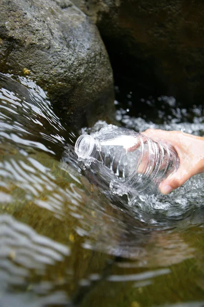 Llenar una botella de agua por un arroyo — Foto de Stock