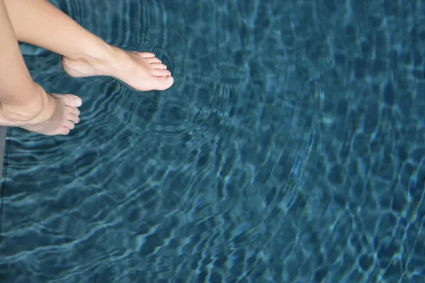 Woman dipping her feet in the swimming pool — Stock Photo, Image