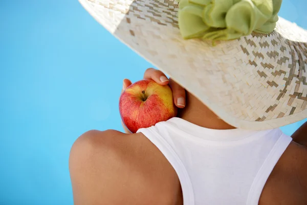 Mulher usando chapéu de verão e segurando uma maçã — Fotografia de Stock