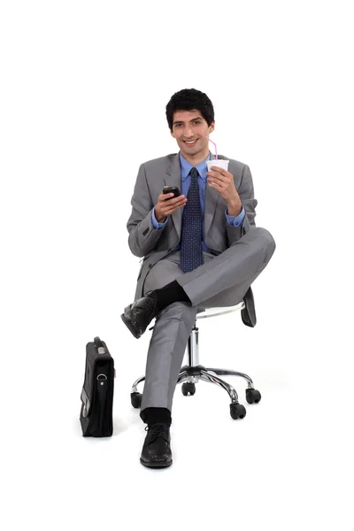 Executive sitting with telephone and refreshment — Stock Photo, Image