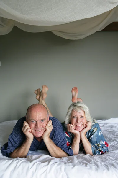 Casal sênior deitado em uma cama — Fotografia de Stock