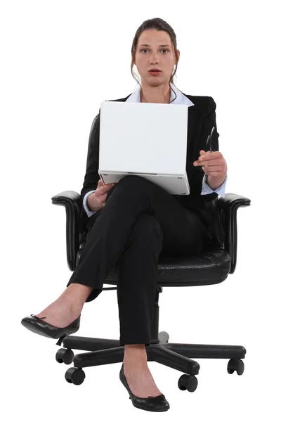 Verrast zakenvrouw zittend in een stoel en holding laptop — Stockfoto