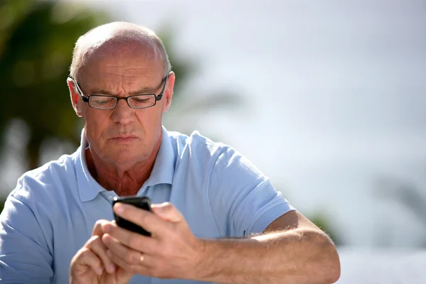 Starší muž odesílání SMS — Stock fotografie