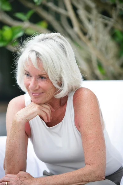 Femme aux cheveux gris assis dans le jardin — Photo