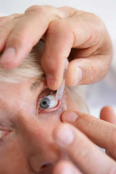Donna anziana mettendo gocce nei suoi occhi — Foto Stock