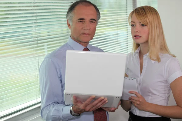 Affärsman tittar på en bärbar dator med hans assistent — Stockfoto