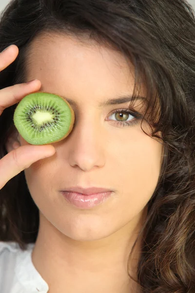 Mujer joven sosteniendo un kiwi — Foto de Stock