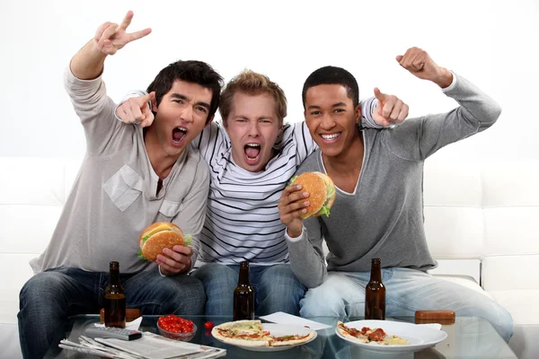 Három meg étkezés közben nézi a televíziót — Stock Fotó