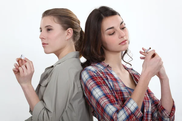 Chica encendiendo un cigarrillo como otro chasquea uno por la mitad — Foto de Stock