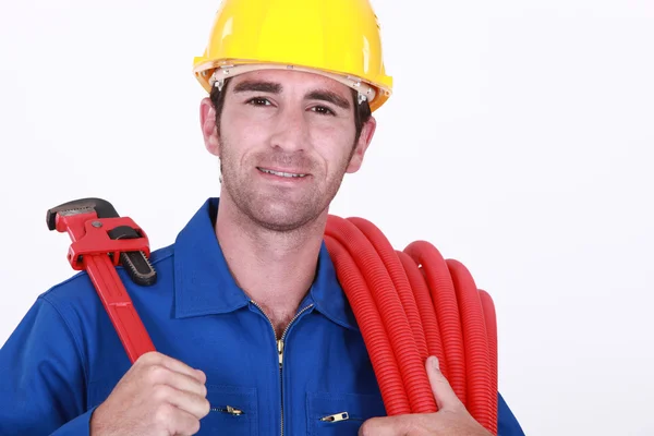 Portret van vrolijke loodgieter boekwaarde slang en spanner — Stockfoto