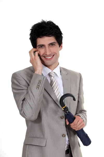 Geschäftsmann hält Regenschirm in der Hand und telefoniert mit Handy — Stockfoto