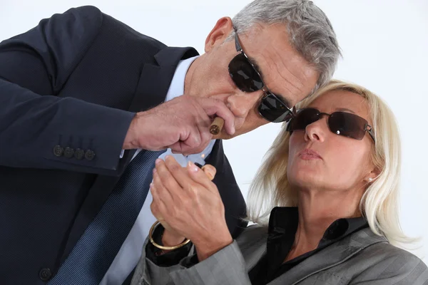 Зрелый джентльмен курит сигары с блондинкой супруга хвастается — стоковое фото
