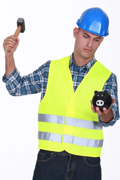 Construction worker breaking open a piggy bank — Stock Photo, Image