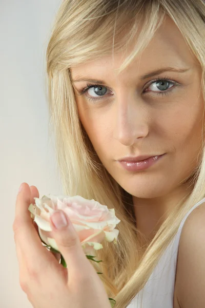 Blonde vrouw die houdt van een bleke roze roos — Stockfoto