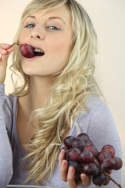 Estúdio tiro de uma jovem mulher comendo uvas — Fotografia de Stock