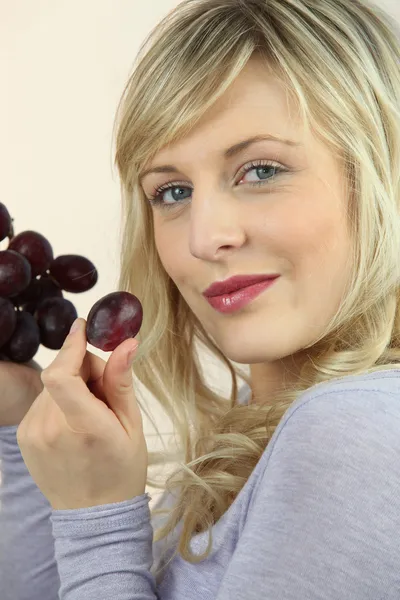 Blond woman eating bunch of grapes Royalty Free Stock Images