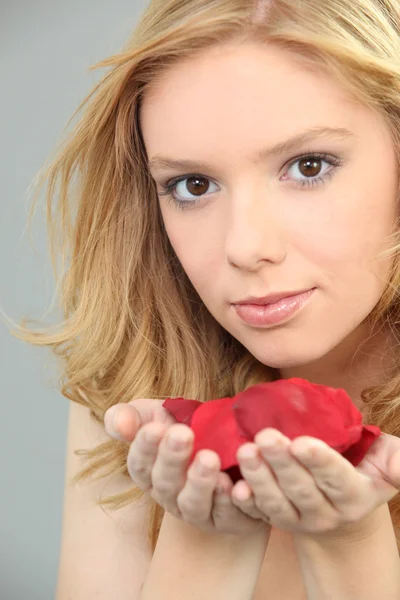 Mujer joven con un puñado de pétalos de rosa — Foto de Stock