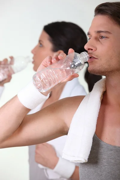 Couple drinking water after a hard gym workout — Stock Photo, Image