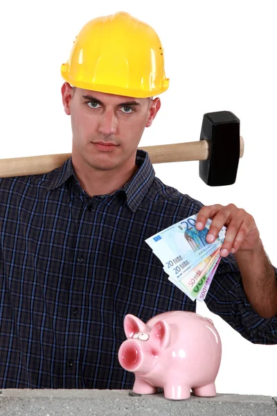 Laborer putting bills in a piggy bank — Stock Photo, Image