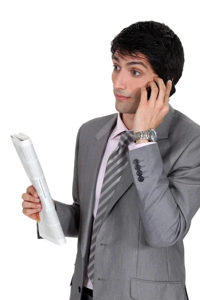 Businessman taking on phone and holding newspaper — Stock Photo, Image