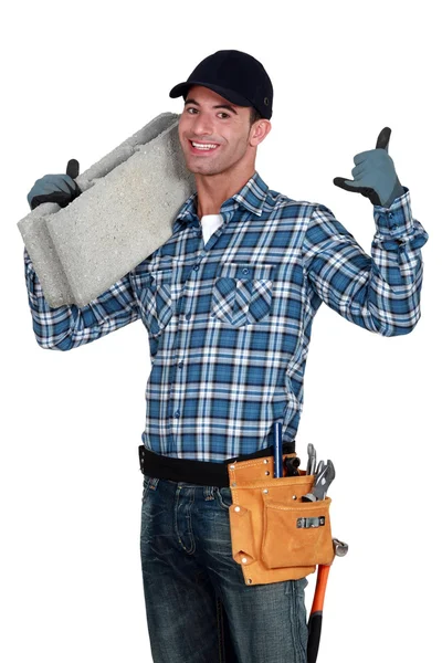 Jovem pedreiro segurando bloco de concreto — Fotografia de Stock