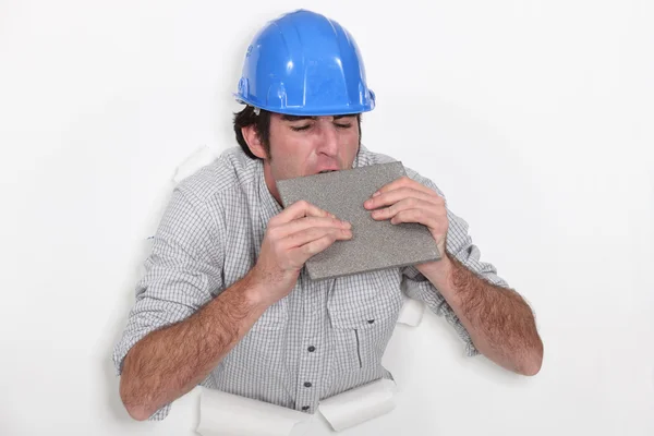 Fed-up tradesman biting a tile — Stock Photo, Image
