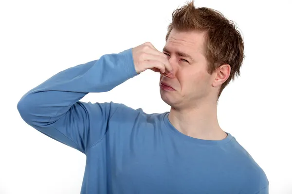 Чоловік тримає ніс проти поганого запаху — стокове фото