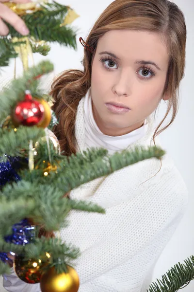 Mujer seria colocando un adorno en un árbol de Navidad — Foto de Stock