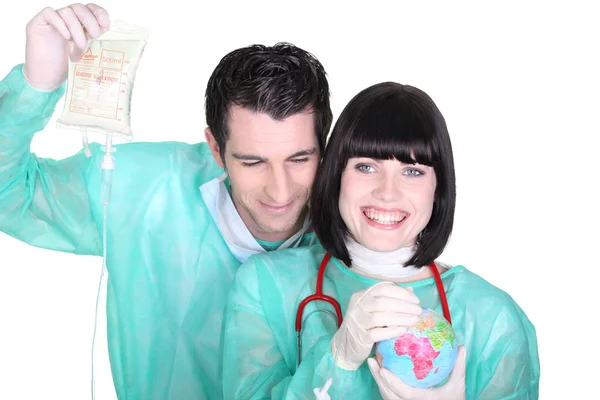 Cheerful medical duo wearing blouse with globe — Stock Photo, Image