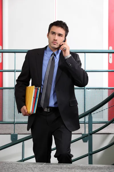 Бизнесмен держит несколько папок во время звонка — стоковое фото