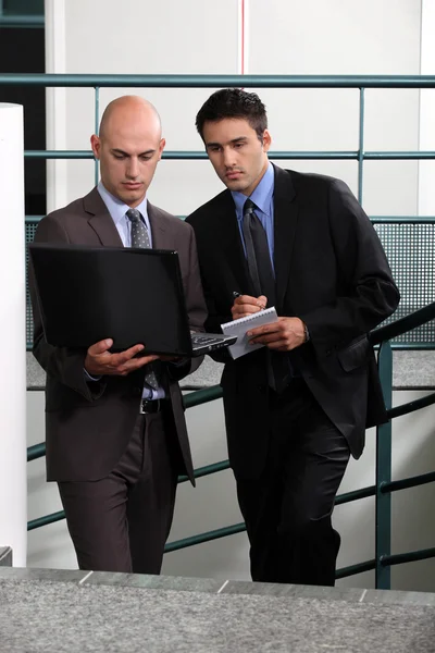 Businessmen comparing notes in stairwell — Stock Photo, Image