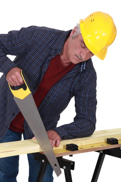 Trabajador de la construcción aserrando una tabla de madera —  Fotos de Stock