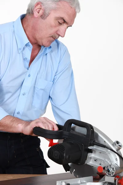 Grey-haired carpenter sawing laminate flooring — Stock Photo, Image