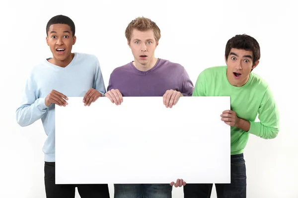 Três homens surpresos segurando cartaz — Fotografia de Stock