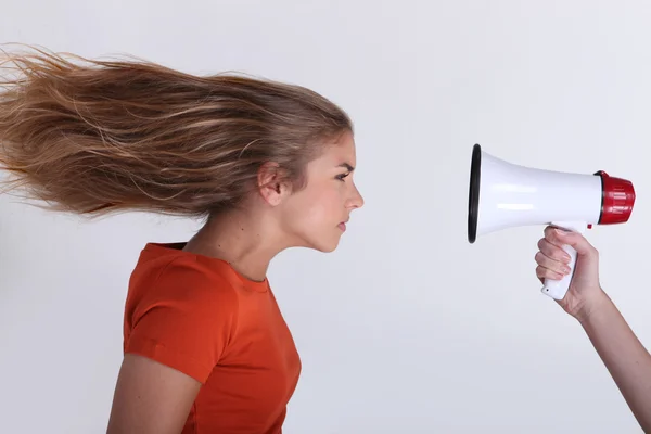 Menina com o cabelo soprado para trás por megafone — Fotografia de Stock