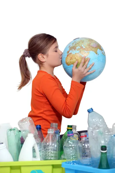 Niña besando planeta tierra junto a su reciclaje — Foto de Stock