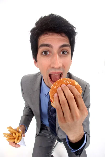 Empresario comiendo comida chatarra — Foto de Stock