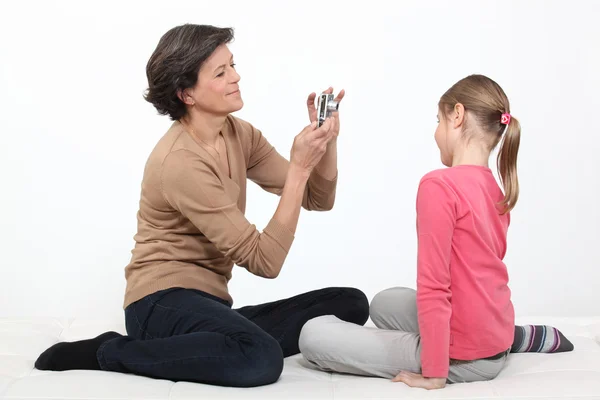 Madre scattare foto di giovane figlia isolata su bianco — Foto Stock