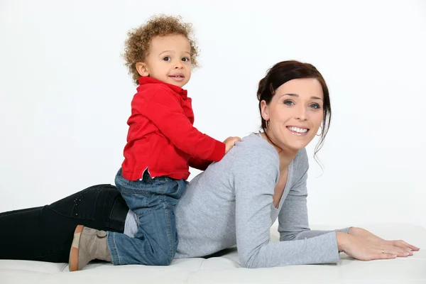 Little boy sitting on the back of his mother — Stock Photo, Image