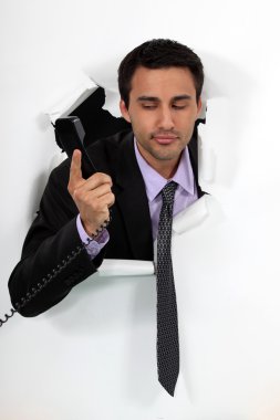 Businessman looking at a telephone handset clipart