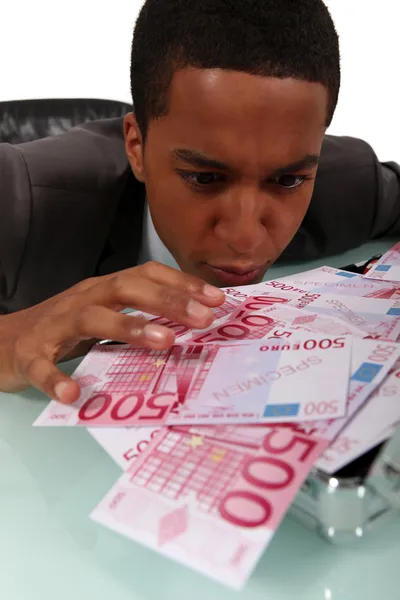 Homem de negócios ávido olhando para as notas em sua mesa — Fotografia de Stock