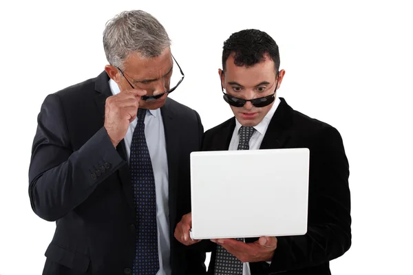 Empresarios con gafas de sol mirando un portátil —  Fotos de Stock