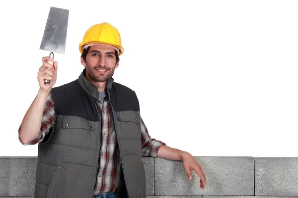 Constructeur avec une truelle seau et mur de bloc — Photo
