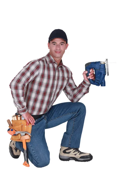 Handwerker kniet und hält eine Bohrmaschine — Stockfoto